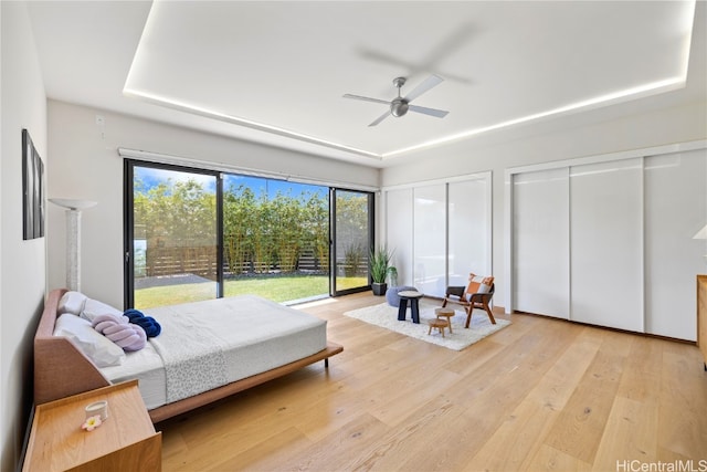 bedroom with light hardwood / wood-style floors, access to exterior, two closets, and ceiling fan