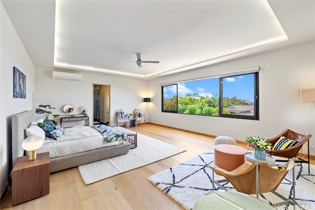 bedroom featuring ceiling fan, a raised ceiling, wood-type flooring, and a wall mounted AC