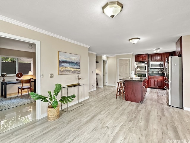 kitchen with light hardwood / wood-style flooring, stainless steel appliances, ornamental molding, a center island, and a kitchen bar