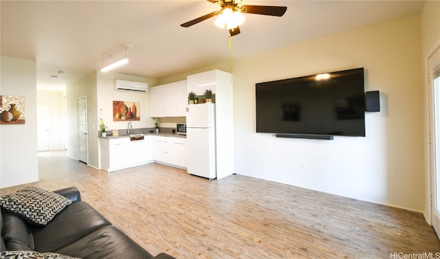 living room with sink, a wall mounted AC, light hardwood / wood-style flooring, and ceiling fan