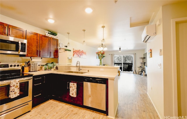 kitchen with kitchen peninsula, a wall mounted AC, appliances with stainless steel finishes, light hardwood / wood-style flooring, and sink