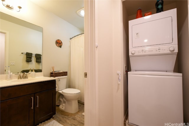 bathroom with vanity, stacked washing maching and dryer, and toilet