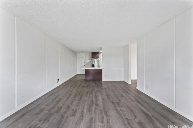 unfurnished living room featuring a textured ceiling and dark hardwood / wood-style flooring