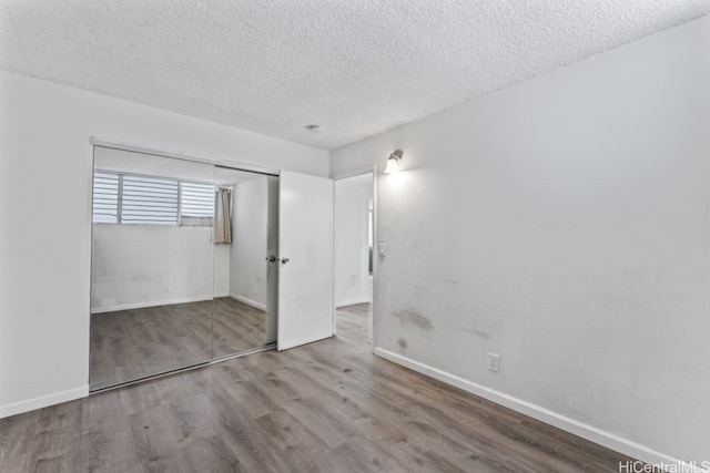 unfurnished bedroom featuring a closet, hardwood / wood-style flooring, and a textured ceiling