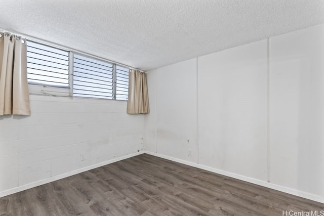 spare room with a textured ceiling and dark hardwood / wood-style floors