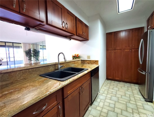 kitchen with light stone countertops, appliances with stainless steel finishes, sink, and kitchen peninsula