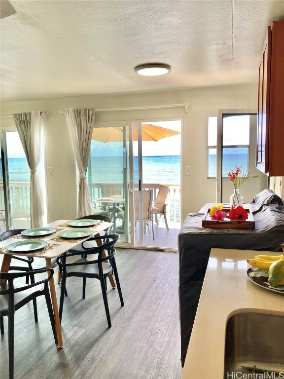 dining space featuring a textured ceiling, light hardwood / wood-style flooring, and a water view