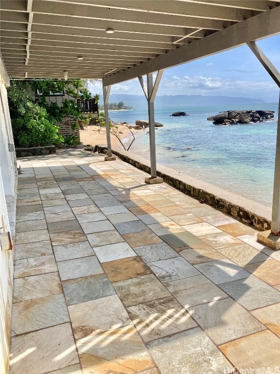 view of patio / terrace with a water view and a beach view