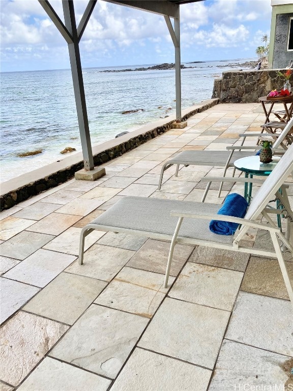 view of patio / terrace featuring a water view and a beach view