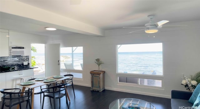 dining room featuring ceiling fan, a water view, and dark hardwood / wood-style flooring