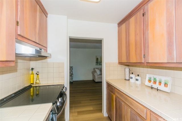 kitchen with tile countertops, decorative backsplash, black range with electric stovetop, and light wood-type flooring