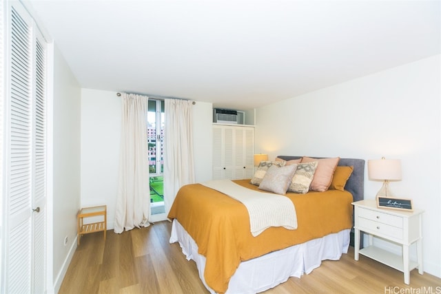 bedroom featuring a wall mounted AC and light hardwood / wood-style flooring