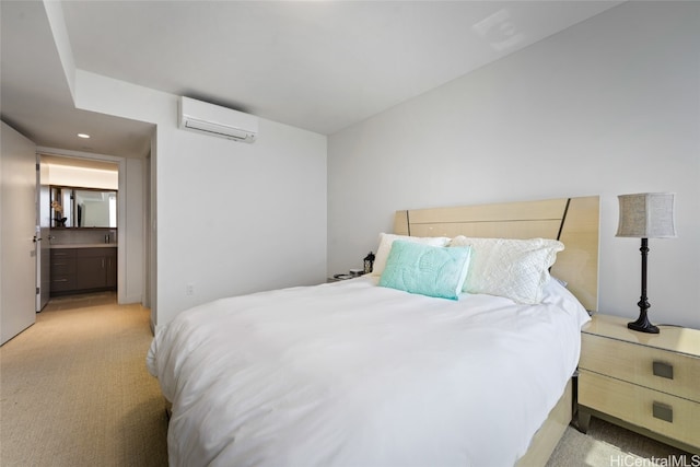 bedroom with a wall unit AC, ensuite bathroom, and light colored carpet