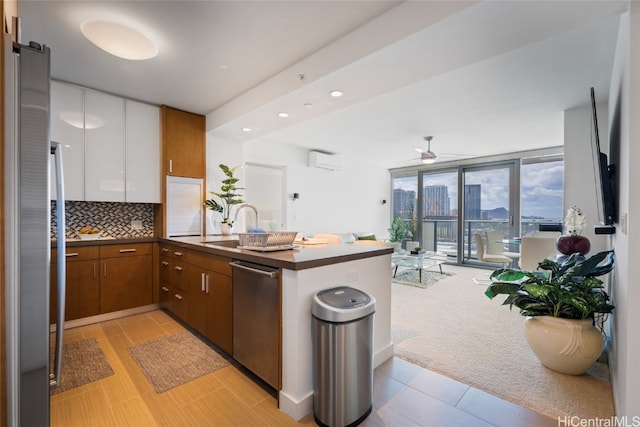 kitchen featuring an AC wall unit, kitchen peninsula, light colored carpet, stainless steel dishwasher, and white cabinets