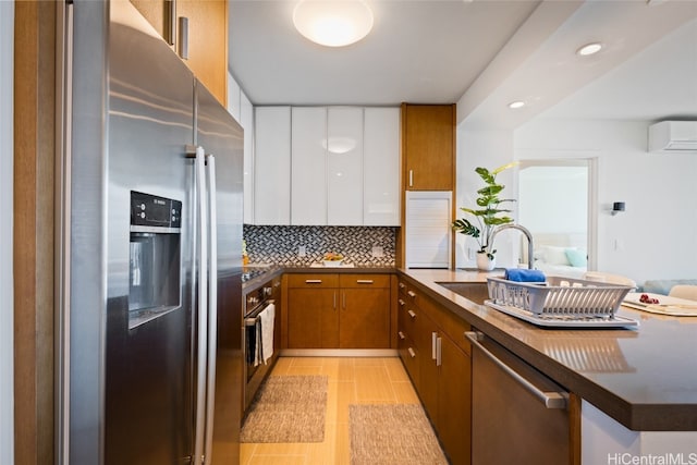 kitchen with a wall unit AC, stainless steel appliances, backsplash, sink, and white cabinets