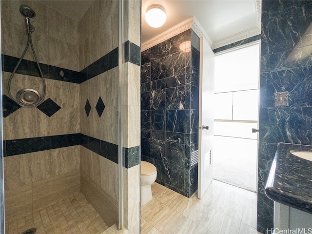 bathroom featuring tile walls, toilet, ornamental molding, tiled shower, and vanity