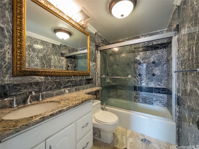 full bathroom with vanity, toilet, tile walls, and shower / bath combination with glass door