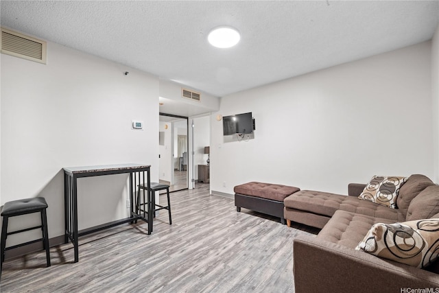 living room featuring baseboards, wood finished floors, and visible vents
