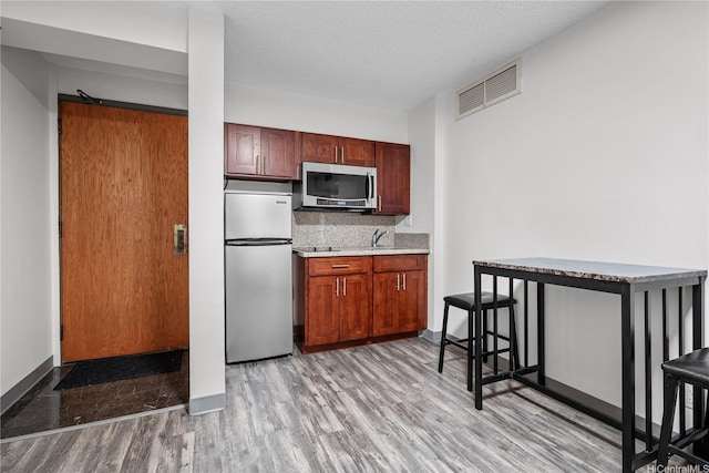 kitchen with visible vents, appliances with stainless steel finishes, tasteful backsplash, light countertops, and light wood-style flooring