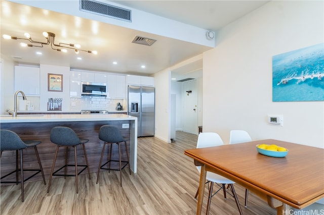 kitchen with white cabinets, decorative backsplash, light hardwood / wood-style flooring, sink, and appliances with stainless steel finishes