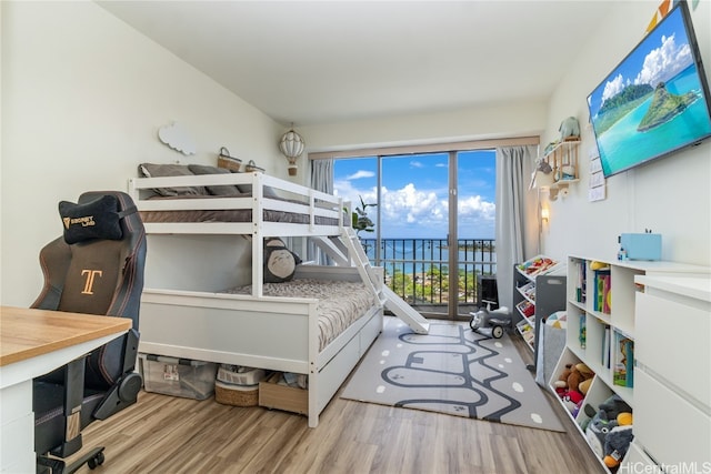 bedroom featuring a water view, light wood-type flooring, and access to outside