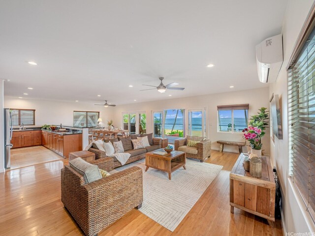 living area with recessed lighting, a ceiling fan, a wall mounted AC, and plenty of natural light