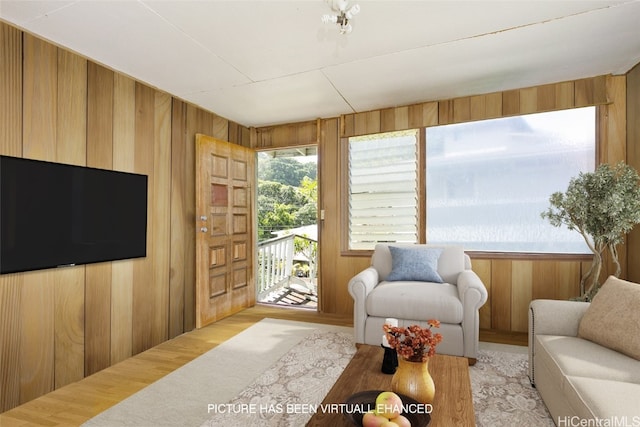 living room featuring light hardwood / wood-style flooring and wood walls