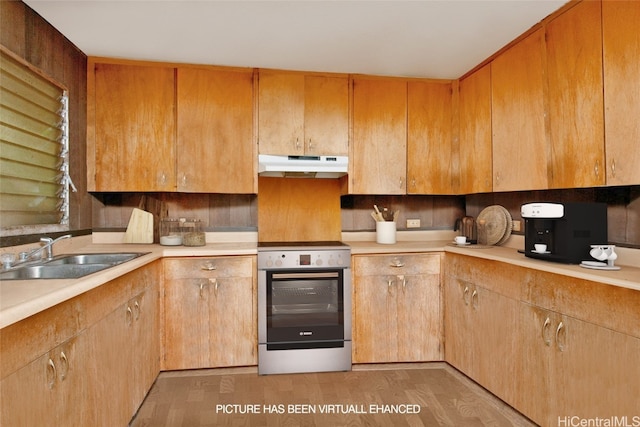 kitchen featuring backsplash, sink, light hardwood / wood-style flooring, and stainless steel stove