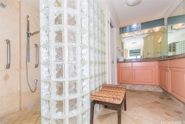 bathroom with tile patterned flooring, vanity, and a tile shower