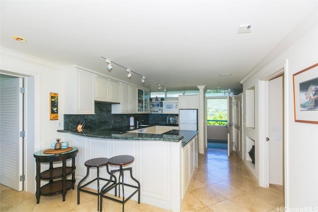 kitchen featuring white appliances, backsplash, white cabinets, light tile patterned floors, and kitchen peninsula