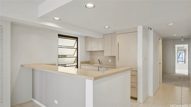 kitchen featuring kitchen peninsula, dishwasher, and light tile patterned flooring