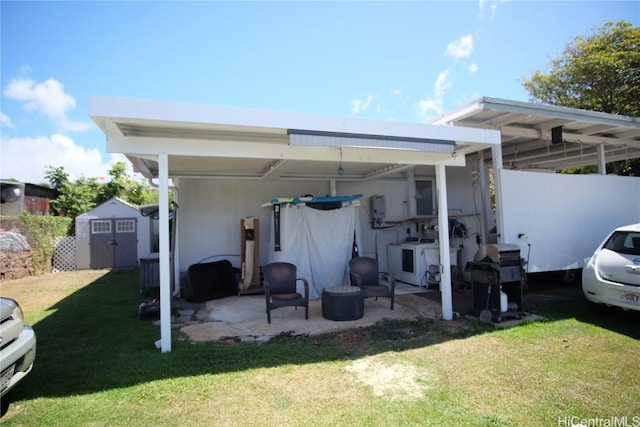 rear view of property with washer / dryer, a patio, a shed, and a lawn