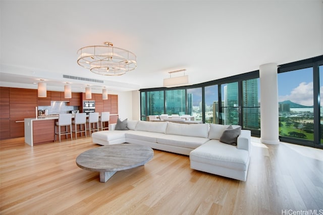 living room with a wealth of natural light, a wall of windows, and light wood-type flooring