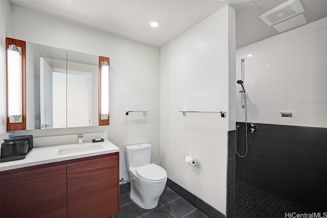 bathroom with vanity, a tile shower, toilet, and tile patterned flooring