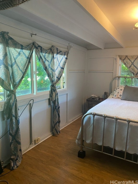 bedroom featuring multiple windows, beamed ceiling, and dark hardwood / wood-style flooring