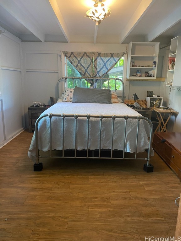 bedroom with beamed ceiling and hardwood / wood-style flooring