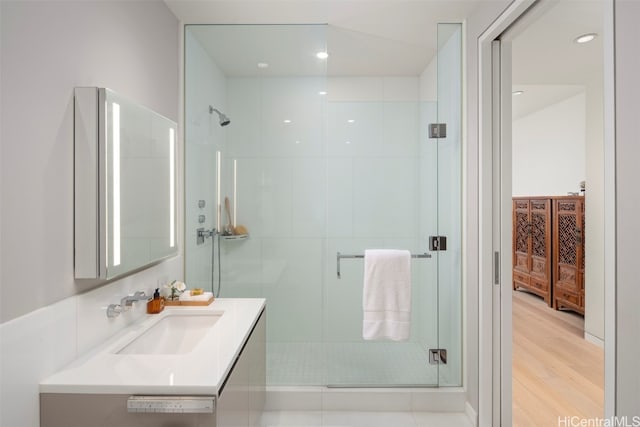 bathroom featuring vanity, a shower with shower door, and wood-type flooring