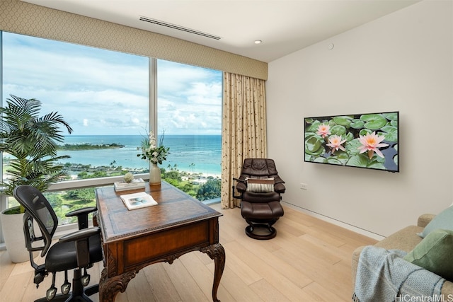 home office featuring light hardwood / wood-style flooring and a water view