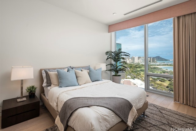 bedroom featuring a water view, multiple windows, and light hardwood / wood-style flooring