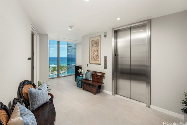 living area featuring a water view, a wall of windows, and elevator