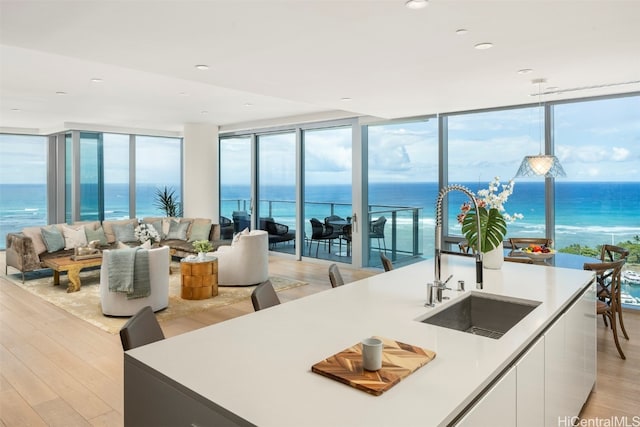 kitchen with pendant lighting, white cabinets, a water view, and light wood-type flooring