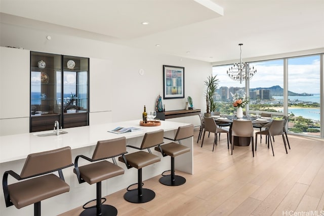 dining area featuring a water view, light hardwood / wood-style floors, sink, and a chandelier