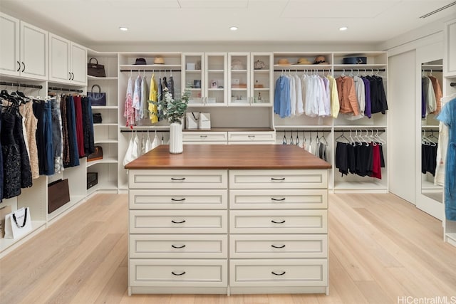 walk in closet with light hardwood / wood-style floors