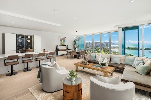 living room with expansive windows, light hardwood / wood-style flooring, and a water view