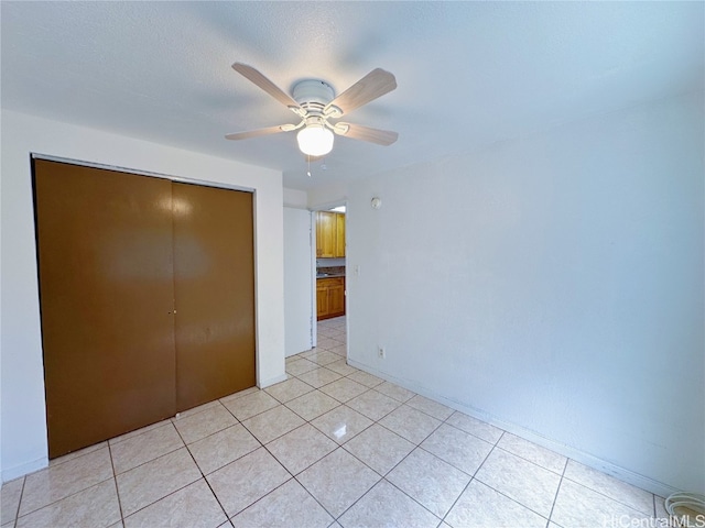 unfurnished bedroom with light tile patterned floors, a closet, and ceiling fan