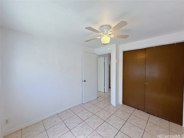 unfurnished bedroom with light tile patterned floors, a closet, and ceiling fan