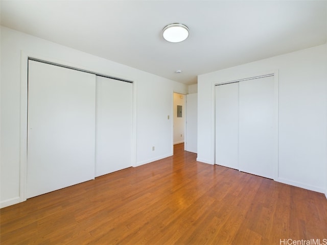 unfurnished bedroom with two closets and hardwood / wood-style flooring