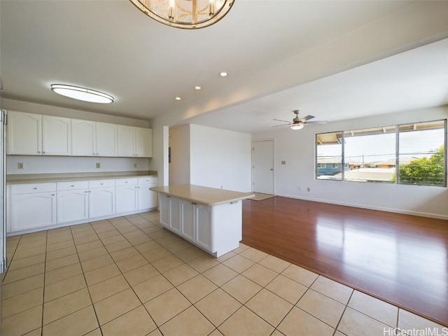 kitchen with white cabinetry, ceiling fan, light wood-type flooring, and a kitchen island