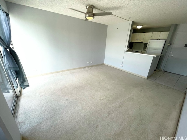 unfurnished living room featuring ceiling fan, a textured ceiling, and light colored carpet