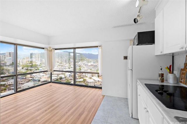 1750 Kalakaua Ave Unit 1611, Honolulu, HI 96826 - kitchen featuring black electric stovetop, a city view, light countertops, healthy amount of natural light, and a textured ceiling